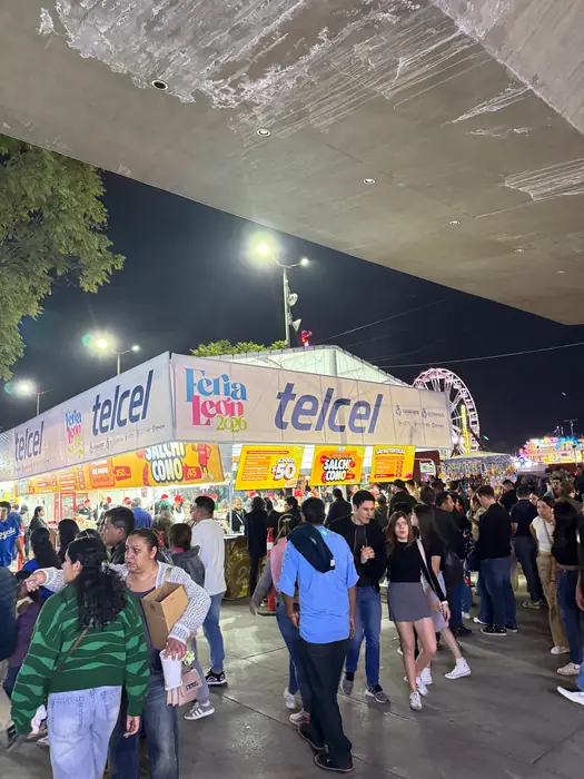 Explanada de la feria por la noche con la rueda de la fortuna al fondo
