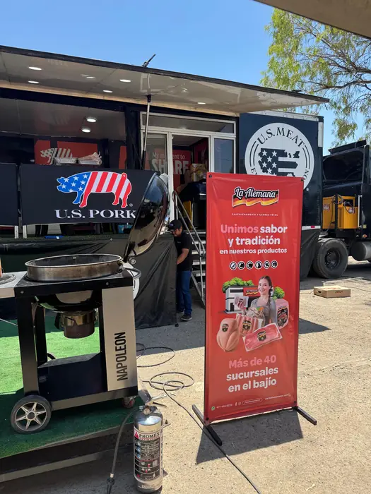 Stand de La Alemana en el festival con la lona “Unimos sabor y tradición” junto al asador