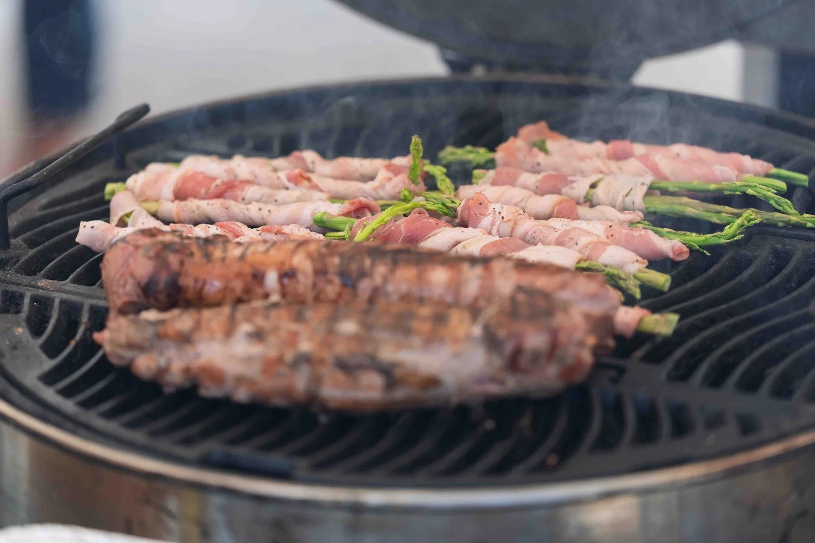 Espárragos envueltos en tocino y cortes asándose en la parrilla